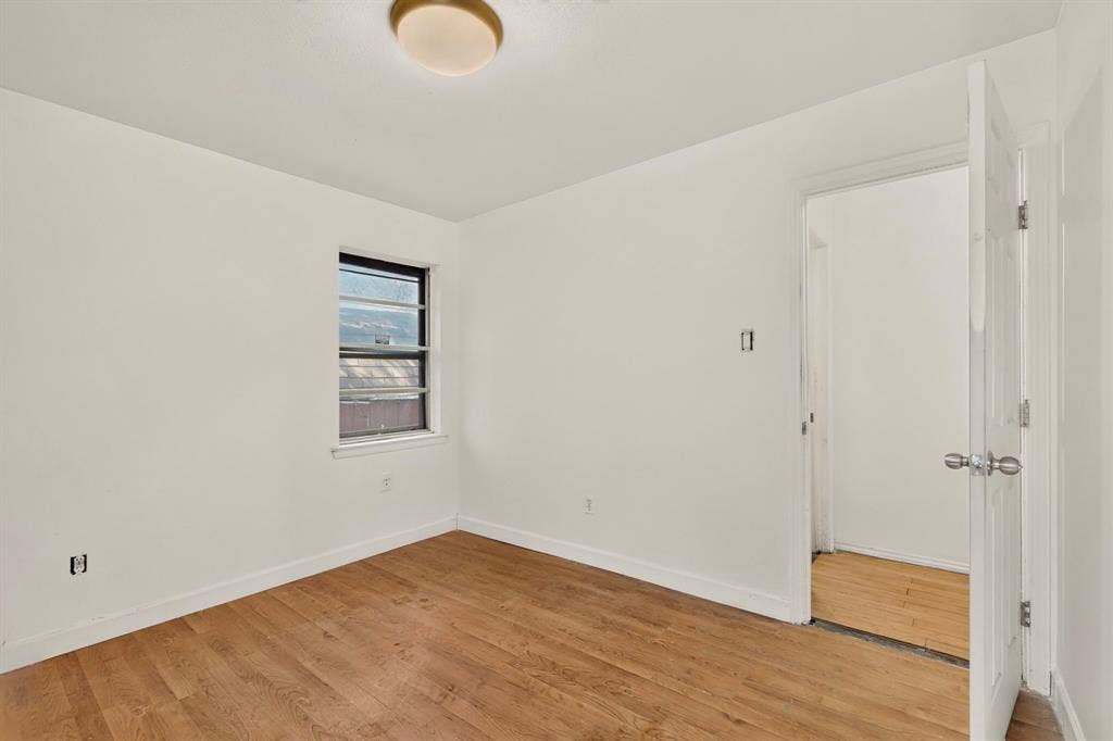 Recessed window with natural light, wood-finish flooring, and a flush-mount ceiling light fixture