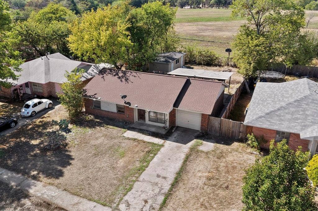 Brick exterior with a brown shingle roof, attached single-car garage, and a concrete driveway