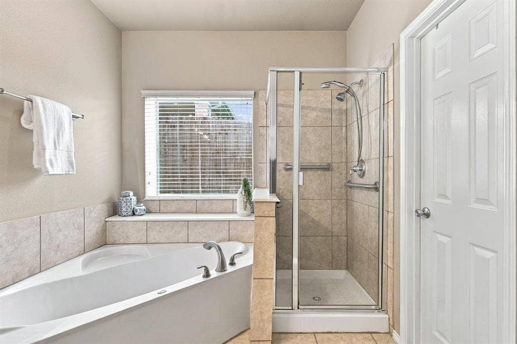 4220 Boxwood Drive, Denton, TX 76208 Corner soaking tub, tiled shower with glass enclosure, chrome fixtures, and a privacy window with blinds
