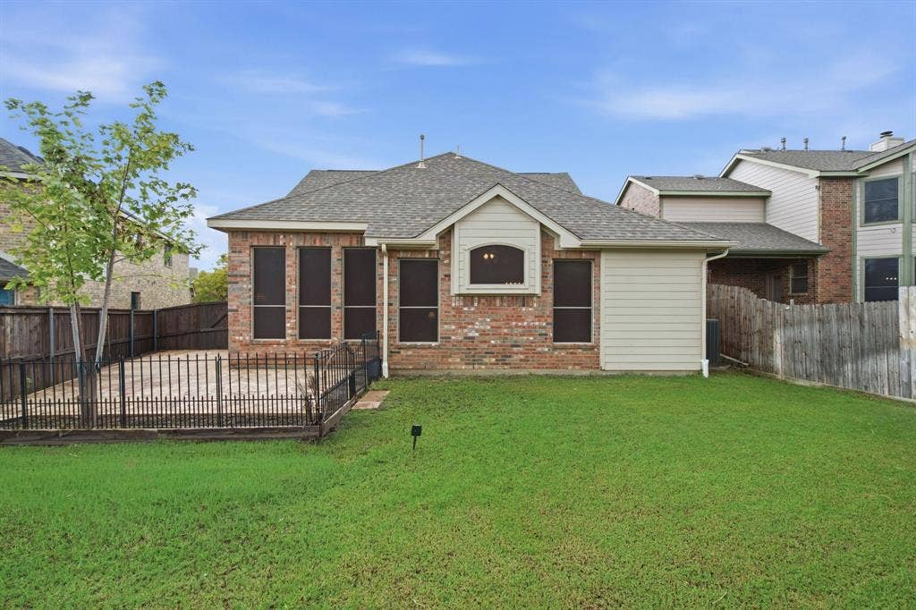 4220 Boxwood Drive, Denton, TX 76208 The metal black fencing can be removed easily. Expansive rear lawn, brick exterior with siding accents, fenced patio area, and architectural shingle roofing