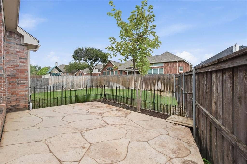 4220 Boxwood Drive, Denton, TX 76208 Expansive stamped concrete patio with direct access to a fenced backyard featuring a manicured lawn and mature landscaping