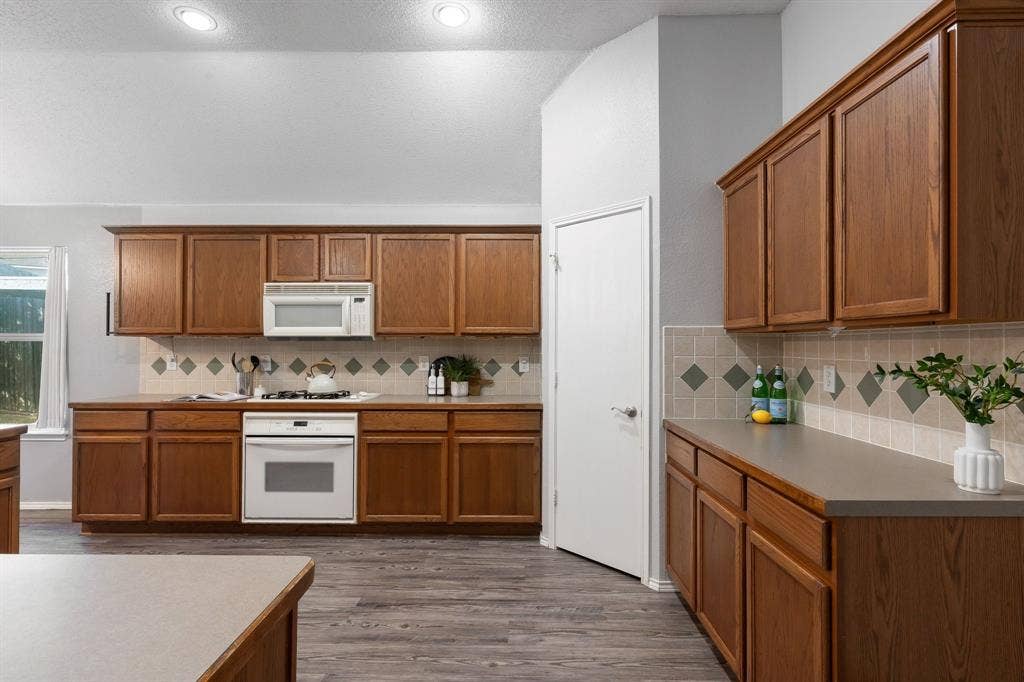 215 Longhorn Trail, Grand Prairie, TX 75052 Kitchen featuring wood cabinetry, light countertops, integrated white appliances, and wood-finish flooring