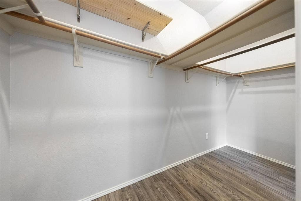 215 Longhorn Trail, Grand Prairie, TX 75052 Walk-in closet featuring wood-finish flooring, white walls, and built-in shelving with hanging rods