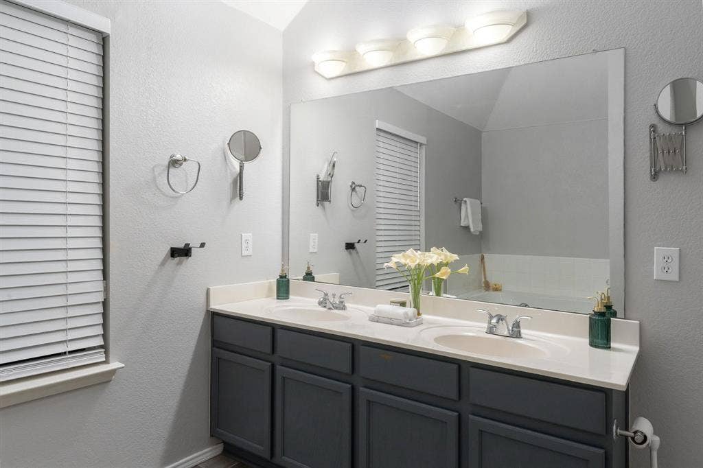215 Longhorn Trail, Grand Prairie, TX 75052 Double vanity with integrated sinks, light-toned countertop, dark-toned cabinetry, and a full-width mirror