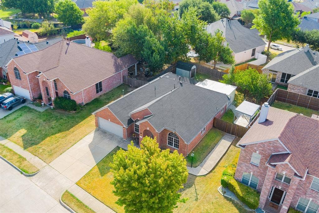 215 Longhorn Trail, Grand Prairie, TX 75052 Brick exterior residence with a dark shingled roof, attached garage, and a concrete driveway