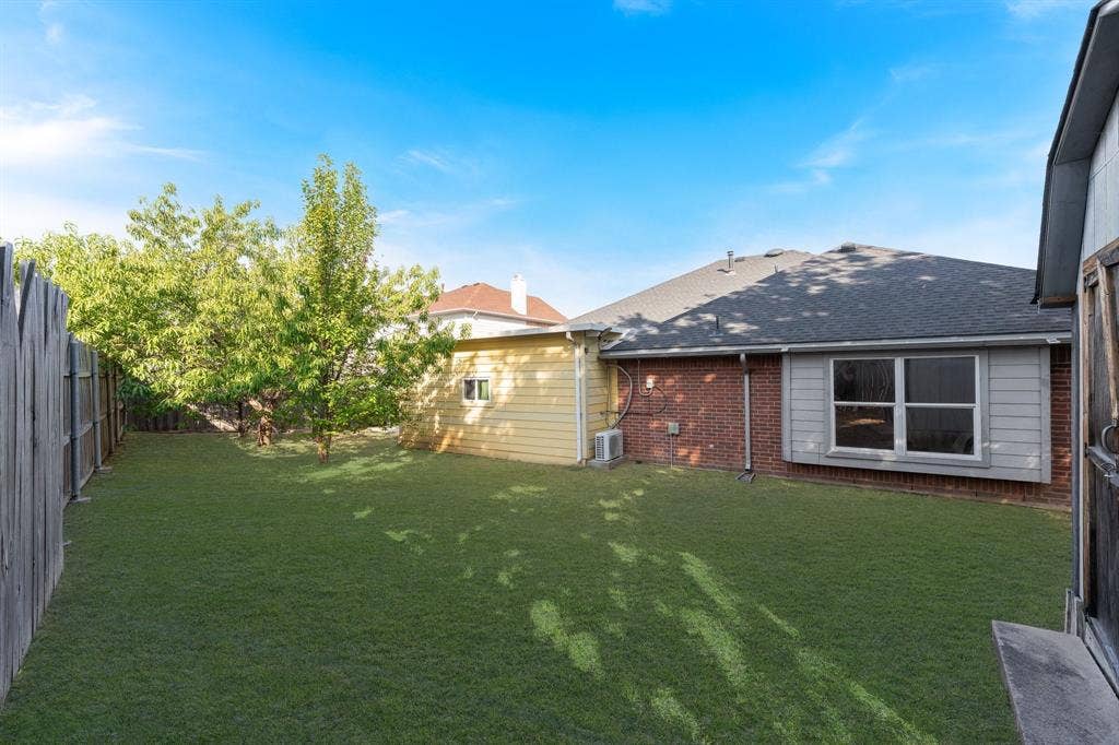 215 Longhorn Trail, Grand Prairie, TX 75052 Expansive backyard featuring a manicured lawn, mature trees, and a wooden privacy fence