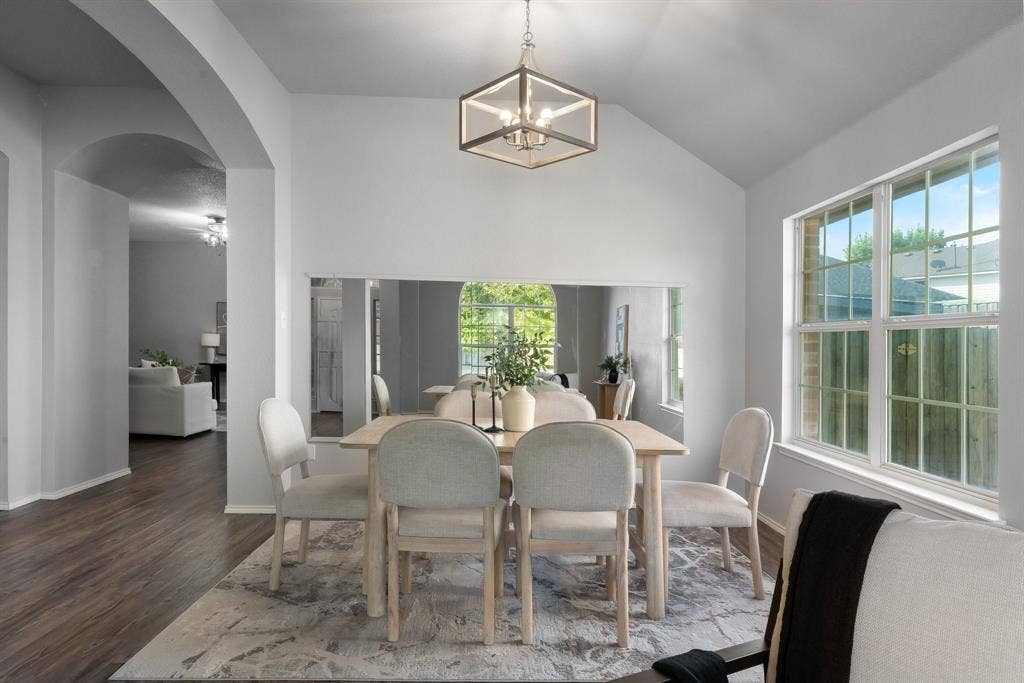 215 Longhorn Trail, Grand Prairie, TX 75052 Vaulted ceiling dining area featuring wood-finish flooring, an arched doorway, and an open geometric pendant light fixture