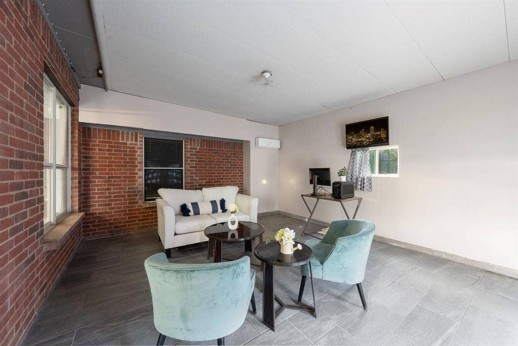 215 Longhorn Trail, Grand Prairie, TX 75052 Brick wall accent, grey tile flooring, window with blinds, ceiling-mounted light fixture, wall-mounted air conditioning unit