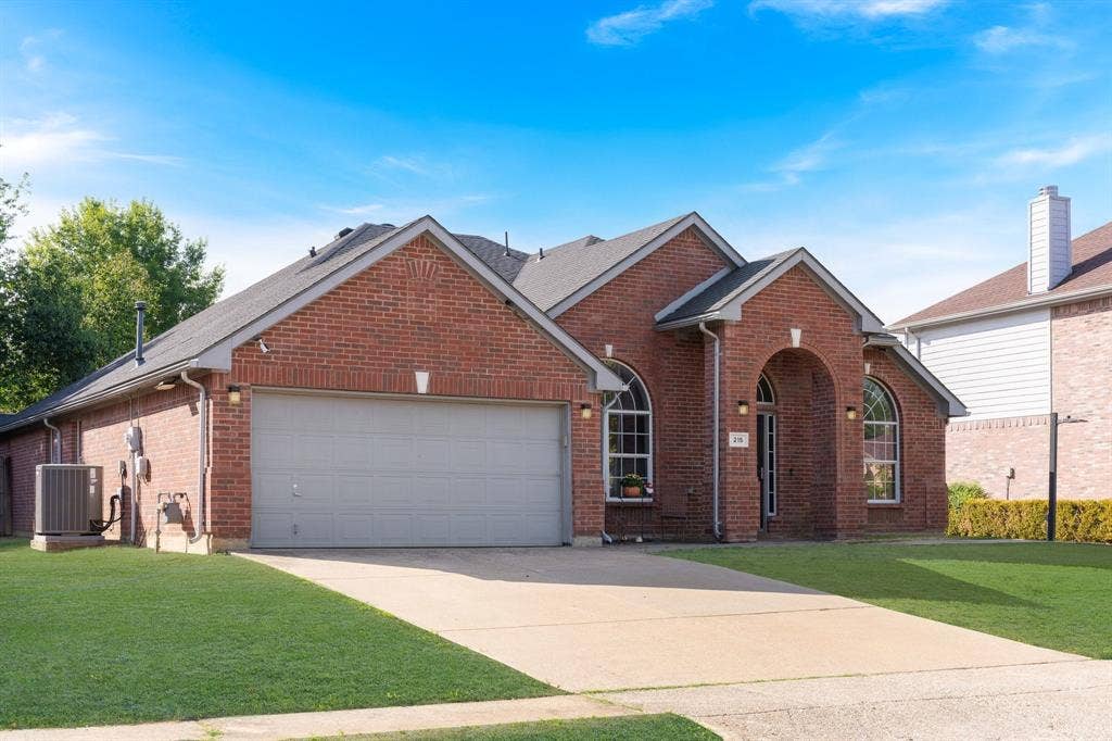 215 Longhorn Trail, Grand Prairie, TX 75052 Brick exterior with arched entry and windows, attached garage, and concrete driveway