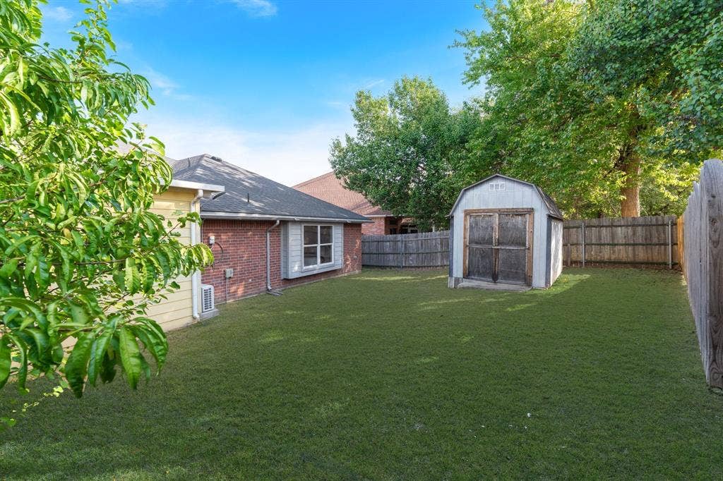 215 Longhorn Trail, Grand Prairie, TX 75052 Expansive grassy yard with a privacy fence, an outbuilding, and mature trees