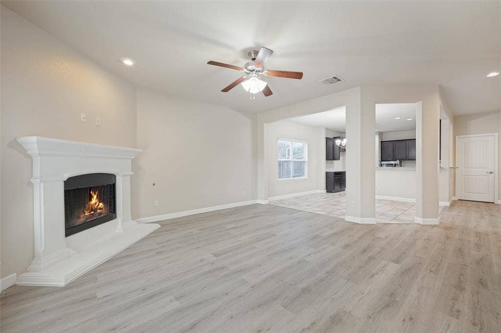 9801 Moccasin Creek Lane, McKinney, TX 75071 Spacious room featuring wood-finish flooring, a white mantel fireplace, recessed lighting, and a ceiling fan