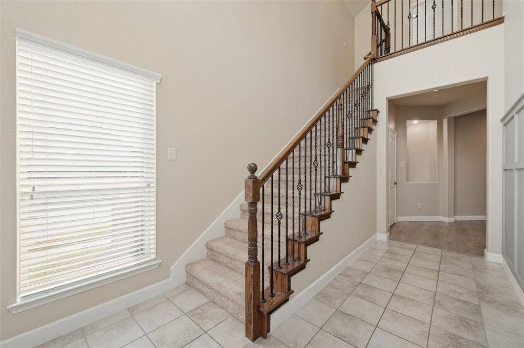 9801 Moccasin Creek Lane, McKinney, TX 75071 Two-story entryway with a carpeted staircase featuring an ornate wrought iron and wood banister