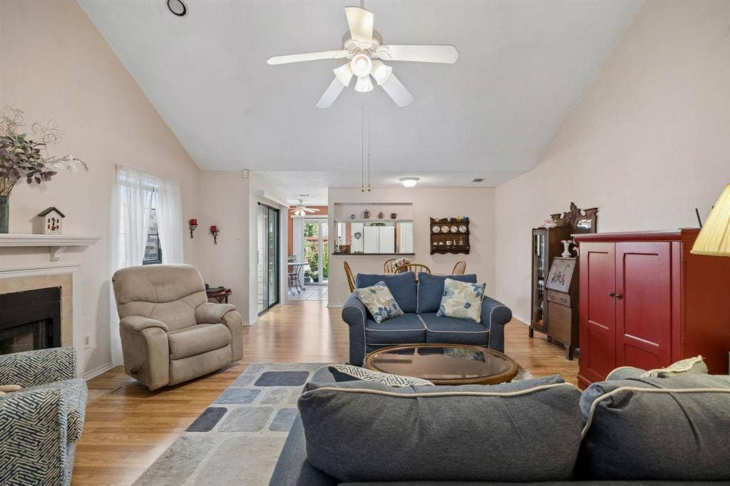 1902 Wyatt Drive, Garland, TX 75040 Vaulted ceilings, wood-finish flooring, fireplace with stone surround, ceiling fan, and sliding glass door