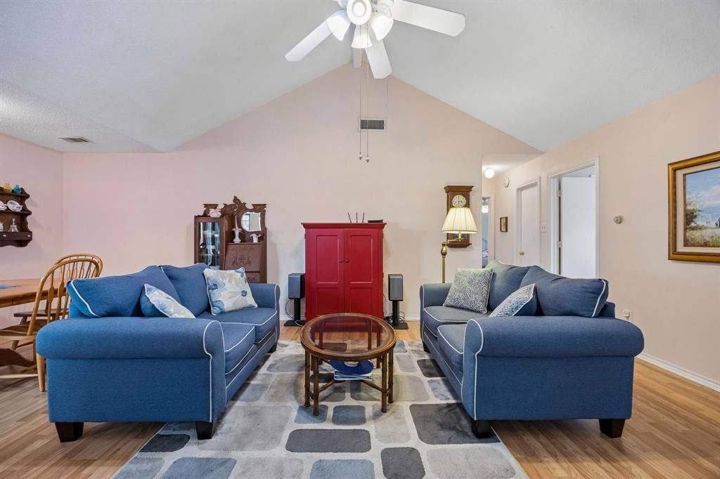 1902 Wyatt Drive, Garland, TX 75040 Spacious living room anchored by vaulted ceilings and a ceiling fan, offering an open floor plan with hardwood flooring throughout