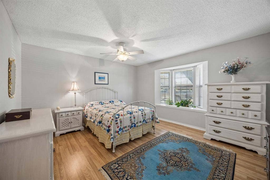 1902 Wyatt Drive, Garland, TX 75040 Wood-finish flooring, bay window with louvered blinds, and a ceiling fan with light fixture