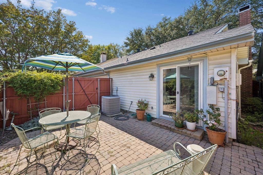 1902 Wyatt Drive, Garland, TX 75040 Paved patio area, white siding exterior, sliding glass door, and red privacy fencing