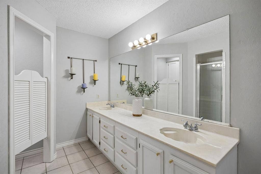 1902 Wyatt Drive, Garland, TX 75040 Spa-inspired primary bathroom featuring a dual-sink vanity with ample storage, white quartz countertops, and an expansive framed mirror
