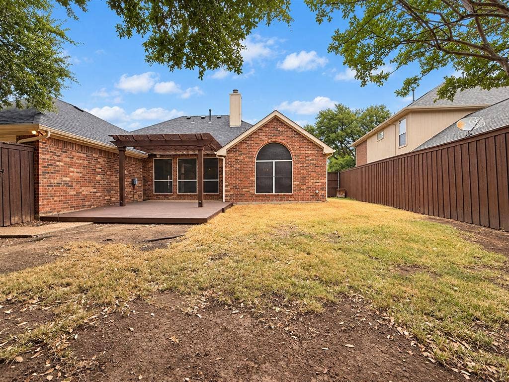 2504 Indian Paint Drive, Plano, TX 75025 Brick exterior with an arched window, featuring a spacious deck with a pergola, and a private wood fence