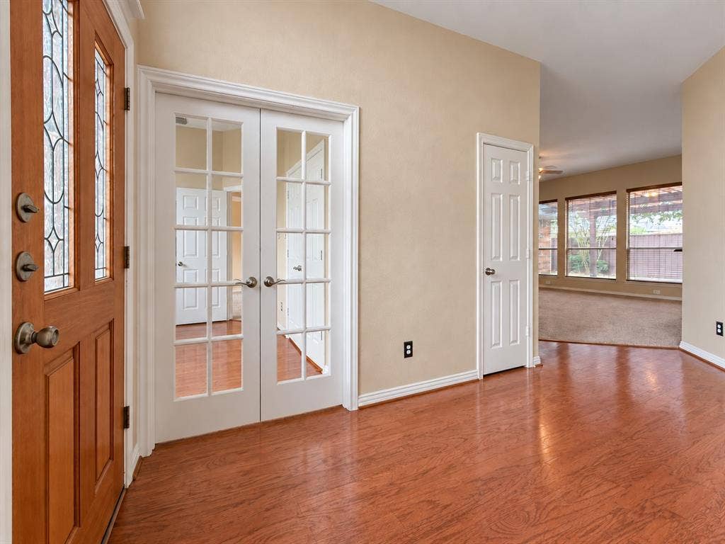 2504 Indian Paint Drive, Plano, TX 75025 Wood-finish flooring, white trim, wood-paneled entry door with decorative glass inserts, and double French doors with glass panes