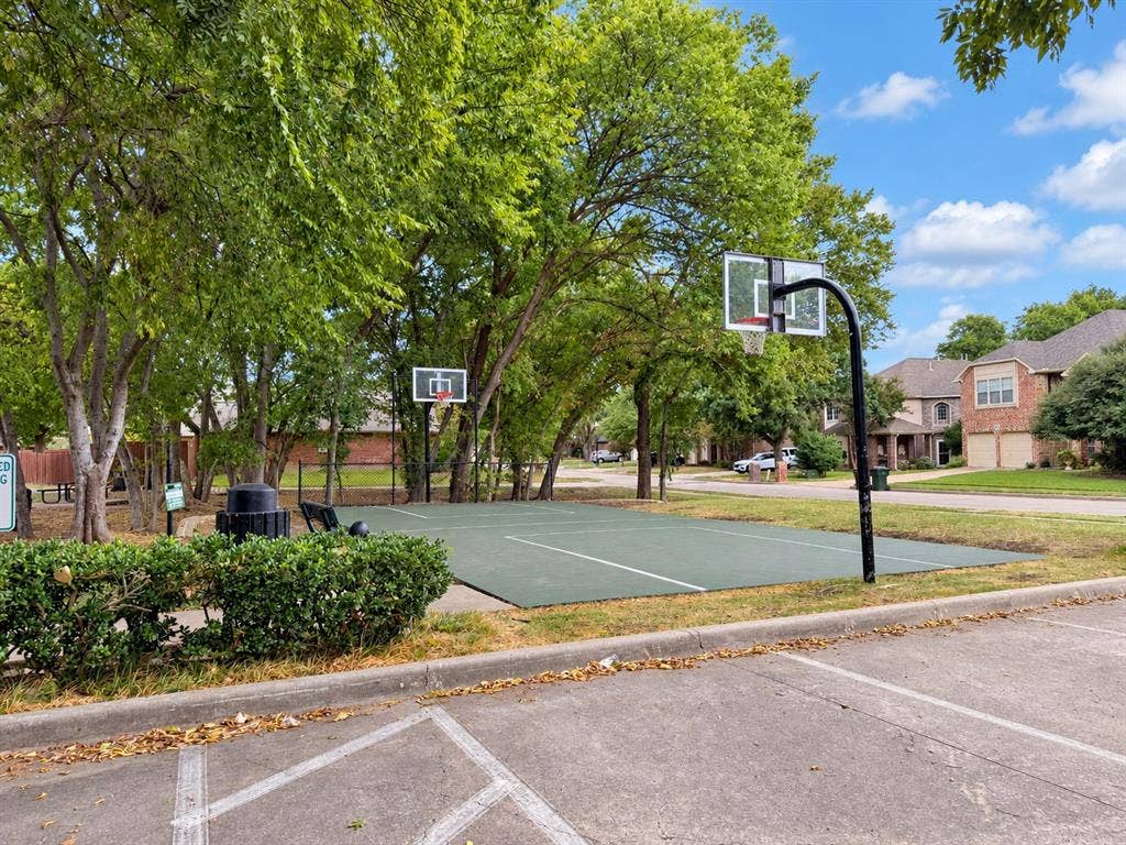 2504 Indian Paint Drive, Plano, TX 75025 Recreational court featuring two basketball hoops, surrounded by mature trees and landscaping