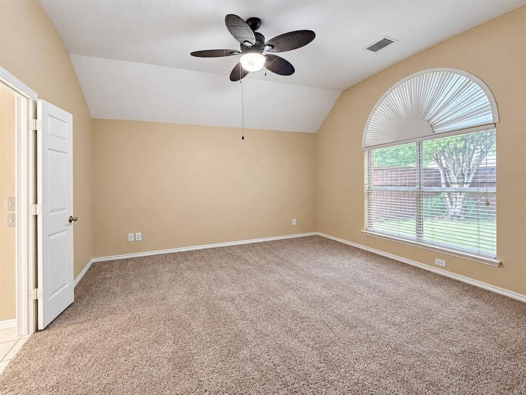 2504 Indian Paint Drive, Plano, TX 75025 Vaulted ceiling room with textured carpeting, a ceiling fan, and a large arched window