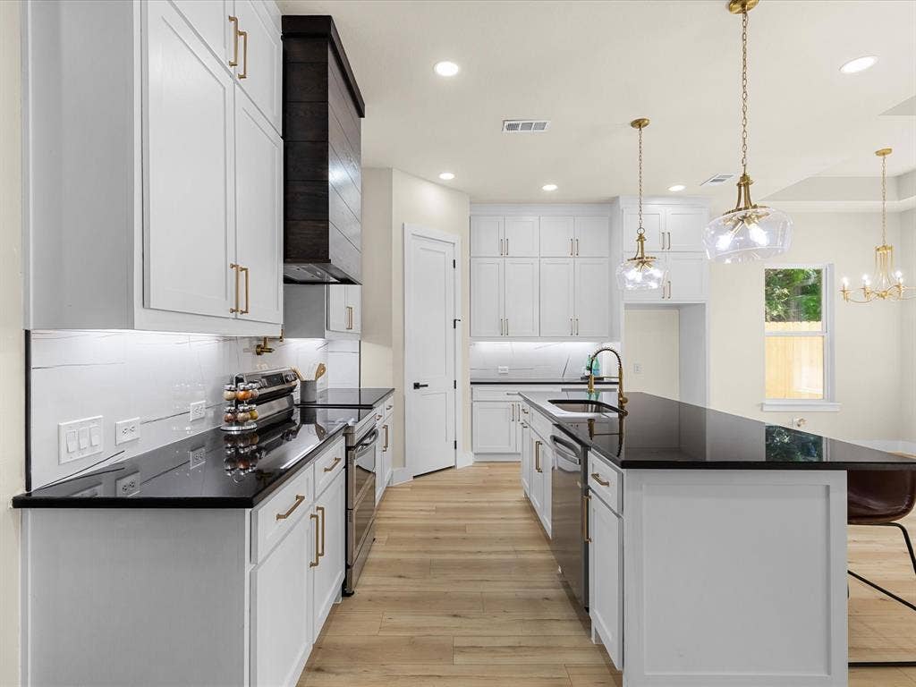 2127 Amanda Avenue, Fort Worth, TX 76105 Kitchen featuring white cabinetry, dark countertops, wood-finish flooring, stainless steel appliances, and gold-finish hardware