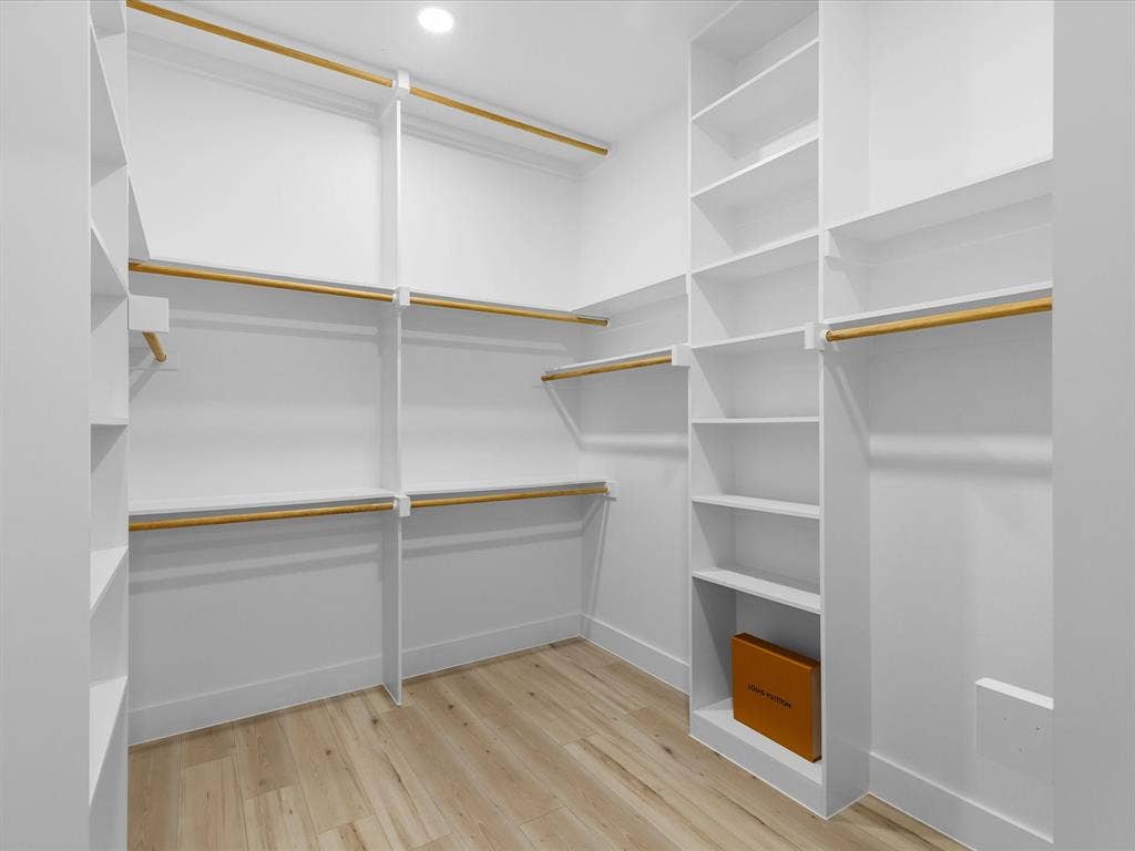 2127 Amanda Avenue, Fort Worth, TX 76105 Spacious walk-in closet featuring built-in shelving, multiple hanging rods, and light-toned wood-finish flooring