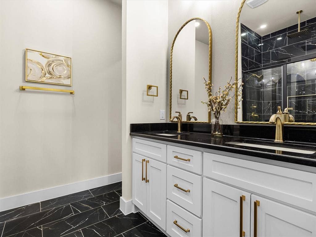 2127 Amanda Avenue, Fort Worth, TX 76105 Dual vanity with white cabinetry, gold-tone hardware, and dark countertops