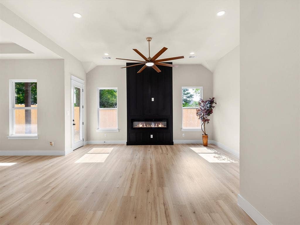 2127 Amanda Avenue, Fort Worth, TX 76105 Vaulted ceiling with recessed lighting, wood-finish flooring, and a modern fireplace with a black accent wall