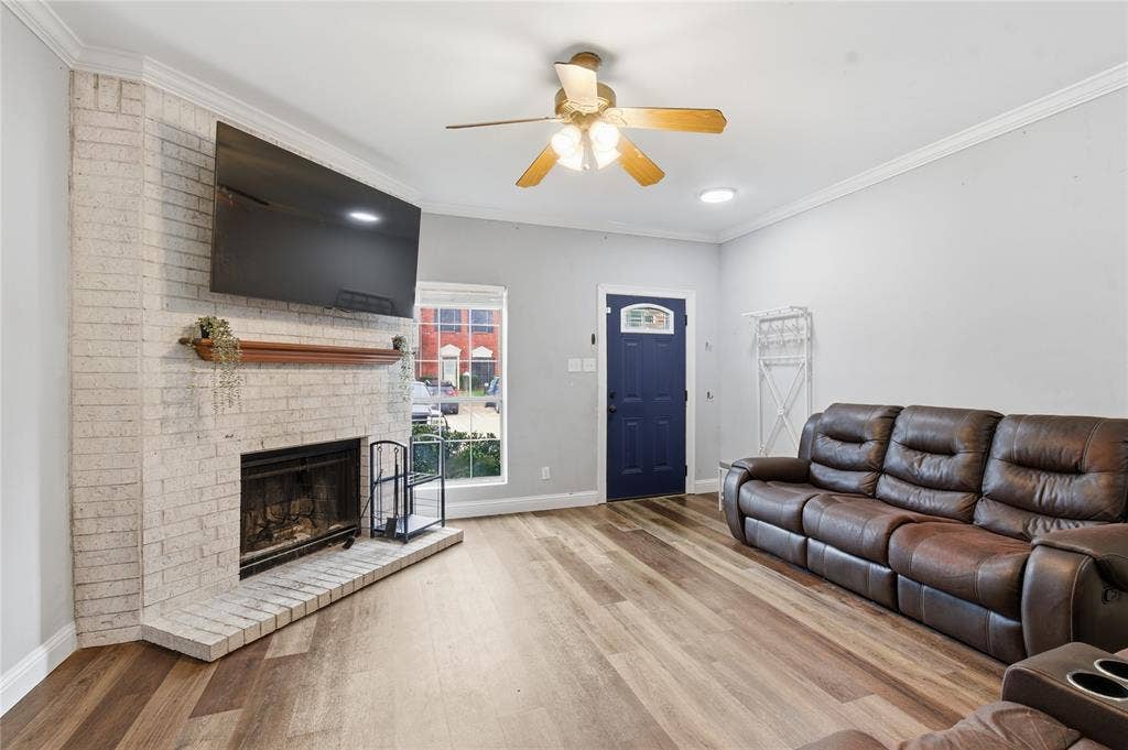 212 Samuel Boulevard, #3, Coppell, TX 75019 Corner fireplace with a wood mantel, wood-finish flooring, accent front door with decorative glass, and a ceiling fan with integrated lighting