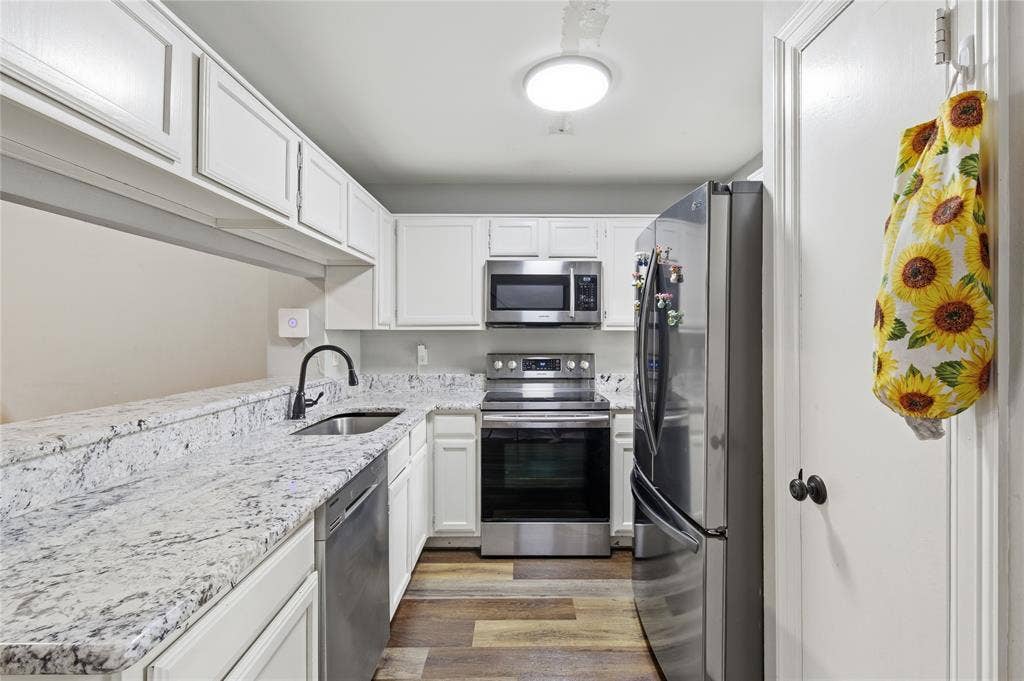 212 Samuel Boulevard, #3, Coppell, TX 75019 Updated kitchen featuring white cabinetry, granite-finish countertops, stainless steel appliances, a black gooseneck faucet, and wood-finish flooring