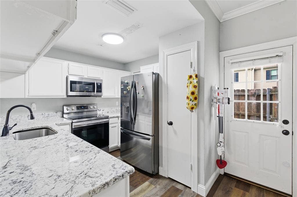 212 Samuel Boulevard, #3, Coppell, TX 75019 Kitchen featuring white cabinetry, stainless steel appliances, speckled countertops, a stainless steel sink with a matte black faucet, and wood-finish flooring