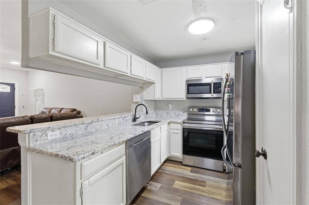 212 Samuel Boulevard, #3, Coppell, TX 75019 Bright kitchen featuring white cabinetry, light-toned countertops, stainless steel appliances, and wood-finish flooring