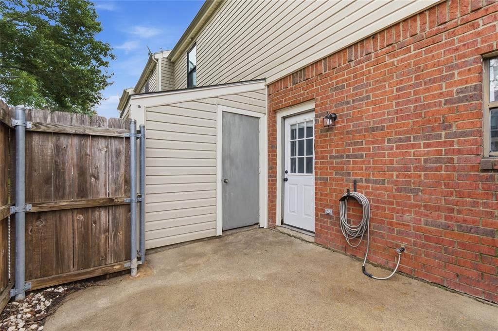 212 Samuel Boulevard, #3, Coppell, TX 75019 Brick exterior with white door, concrete patio, wood fence, and attached storage shed