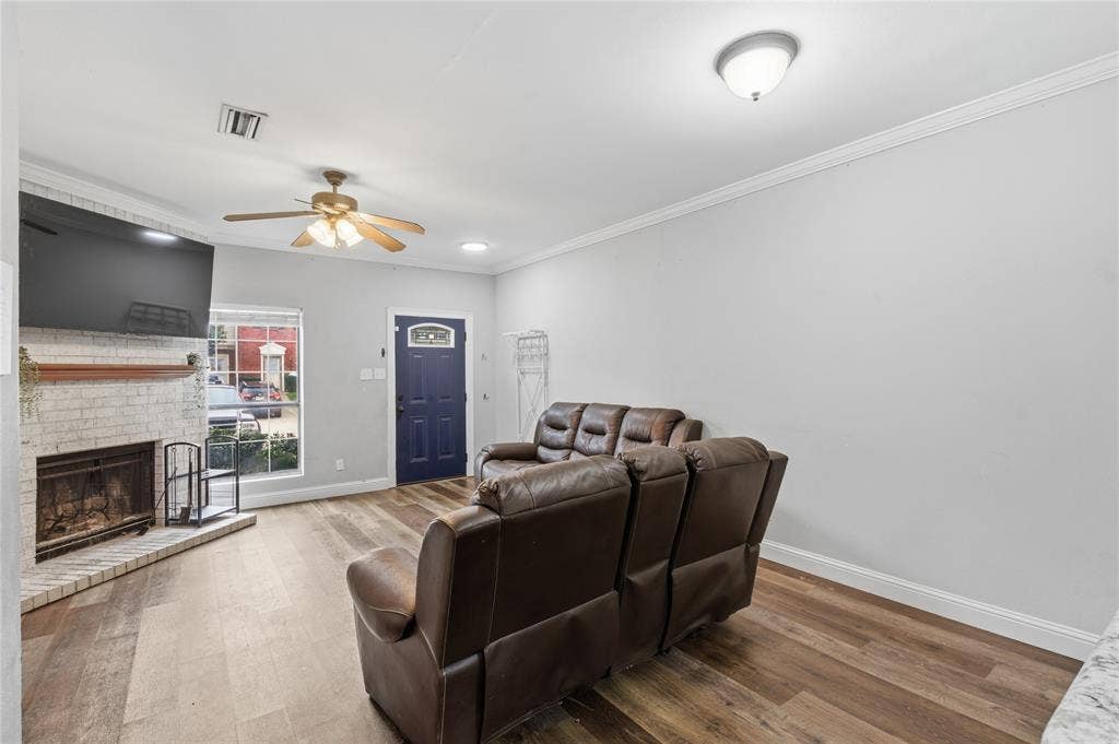 212 Samuel Boulevard, #3, Coppell, TX 75019 Living area with wood-finish flooring, a white brick fireplace, and a ceiling fan with integrated lighting