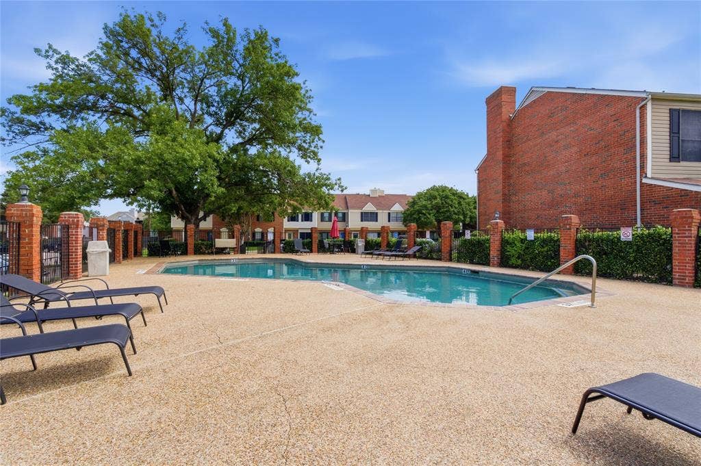 212 Samuel Boulevard, #3, Coppell, TX 75019 Outdoor swimming pool with integrated steps, surrounded by a textured concrete deck, brick pillars, and manicured hedges