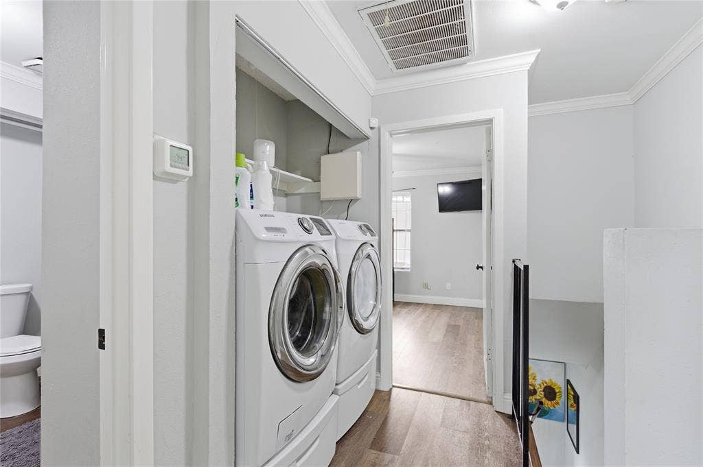212 Samuel Boulevard, #3, Coppell, TX 75019 Laundry area featuring front-loading machines and overhead shelving, wood-finish flooring, crown molding, and a visible thermostat