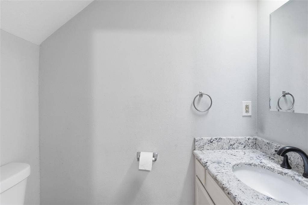 212 Samuel Boulevard, #3, Coppell, TX 75019 Vanity with a granite countertop, undermount sink, and dark-finish faucet