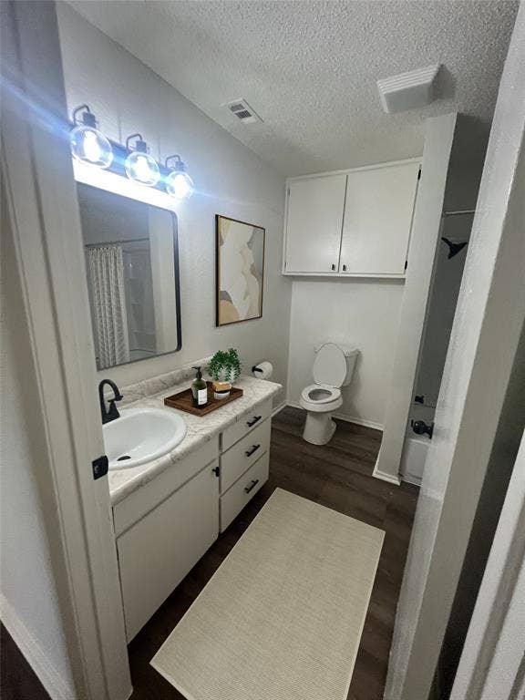 4639 Williams Road, #219, Benbrook, TX 76116 Full bath featuring a textured ceiling, vanity, wood finished floors, and a shower with shower curtain