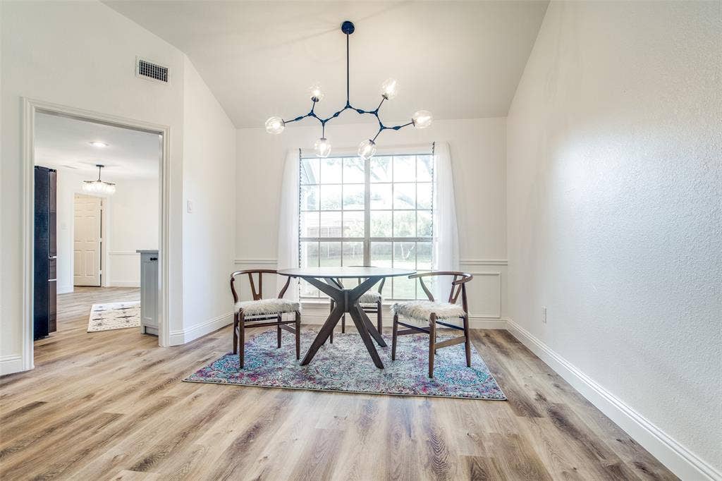 8341 Edgewater Drive, Frisco, TX 75034 Vaulted ceiling with a modern chandelier, wood-finish flooring, and white wainscoting