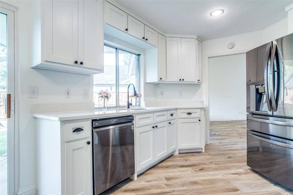 8341 Edgewater Drive, Frisco, TX 75034 White shaker cabinetry, light-toned countertops, stainless steel appliances, wood-finish flooring, and a single-basin sink with a gooseneck faucet