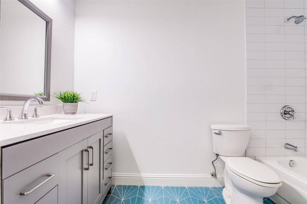 8341 Edgewater Drive, Frisco, TX 75034 Bathroom featuring a light gray vanity with ample storage, white countertop, chrome fixtures, white subway tile shower surround, and blue patterned floor tiles