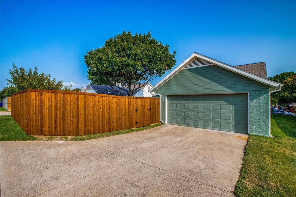 8341 Edgewater Drive, Frisco, TX 75034 Attached garage with a panel door, concrete driveway, and a wood privacy fence