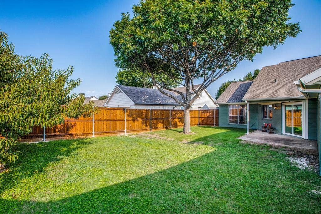 8341 Edgewater Drive, Frisco, TX 75034 Expansive backyard with a manicured lawn, mature trees, wood privacy fencing, and a concrete patio