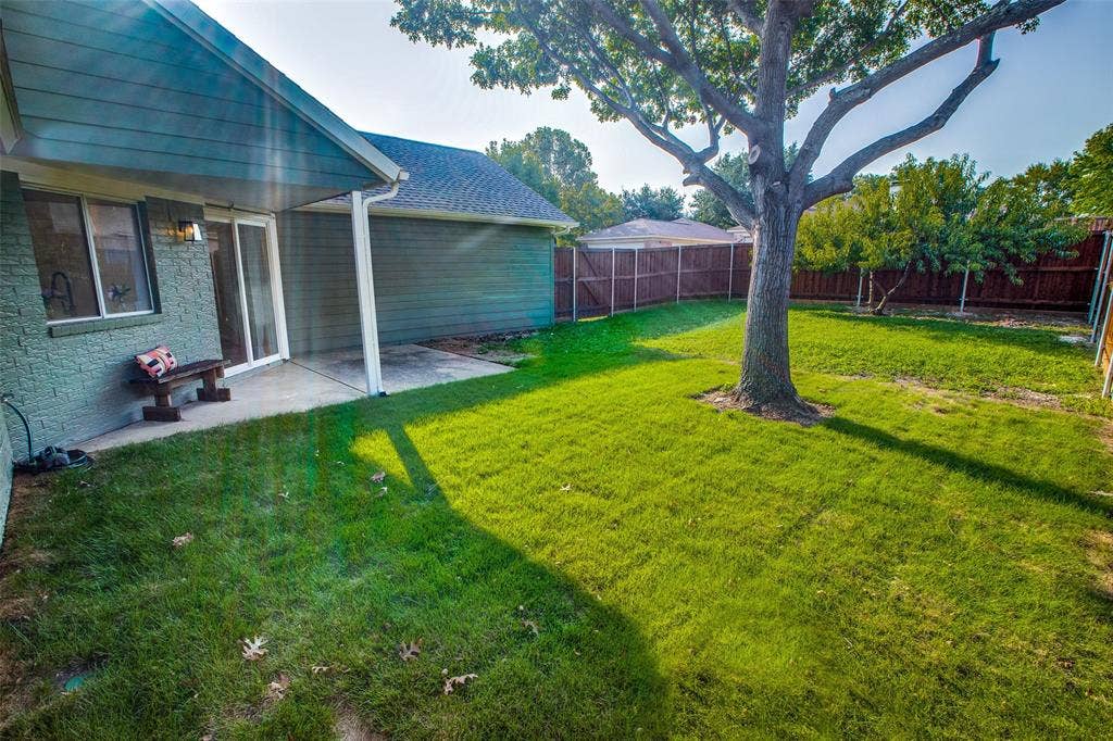 8341 Edgewater Drive, Frisco, TX 75034 Expansive green lawn, mature shade tree, covered patio, privacy fencing, and exterior brick finish