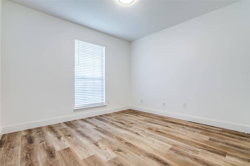 8341 Edgewater Drive, Frisco, TX 75034 Wood-finish flooring, white walls, and a window with blinds