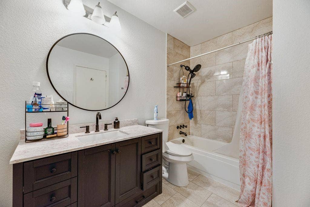 3801 14th Street, #1905, Plano, TX 75074 Dark wood-finish vanity with a light-toned countertop, complete with a single basin sink and dark-toned faucet