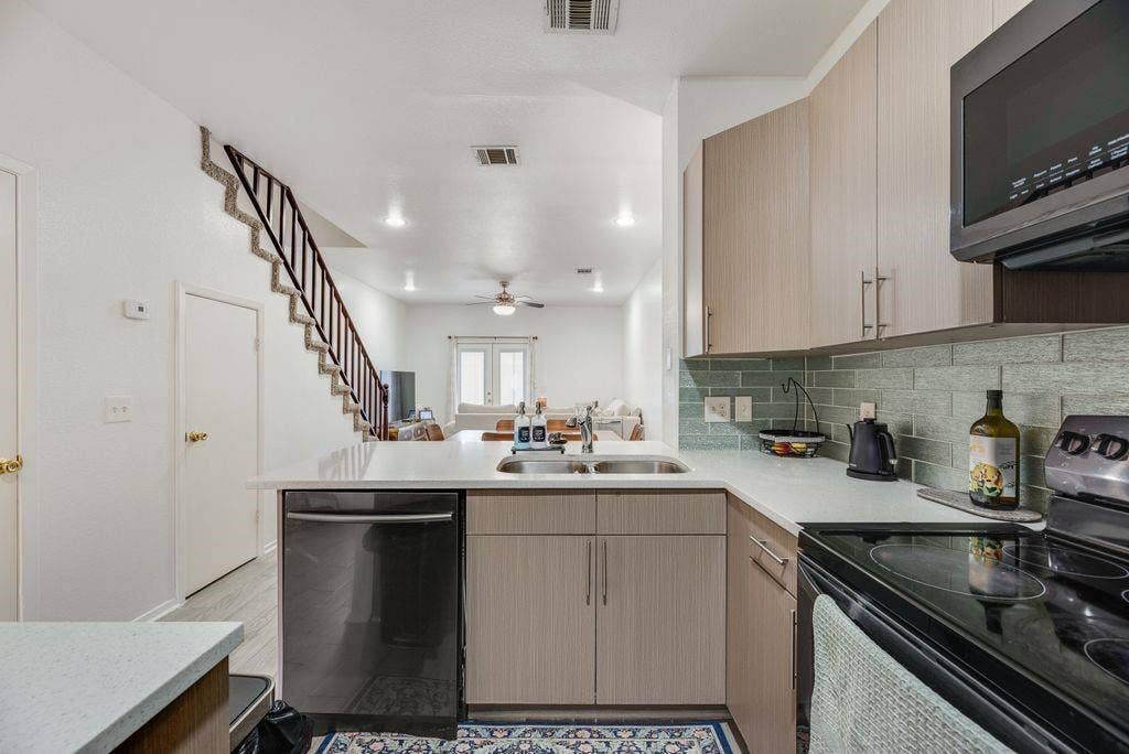 3801 14th Street, #1905, Plano, TX 75074 Modern kitchen featuring light wood-finish cabinetry, stainless steel appliances, white subway tile backsplash, and quartz countertops