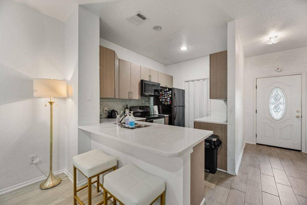 3801 14th Street, #1905, Plano, TX 75074 Compact kitchen featuring light-toned cabinetry, a white countertop with a breakfast bar, and stainless steel appliances
