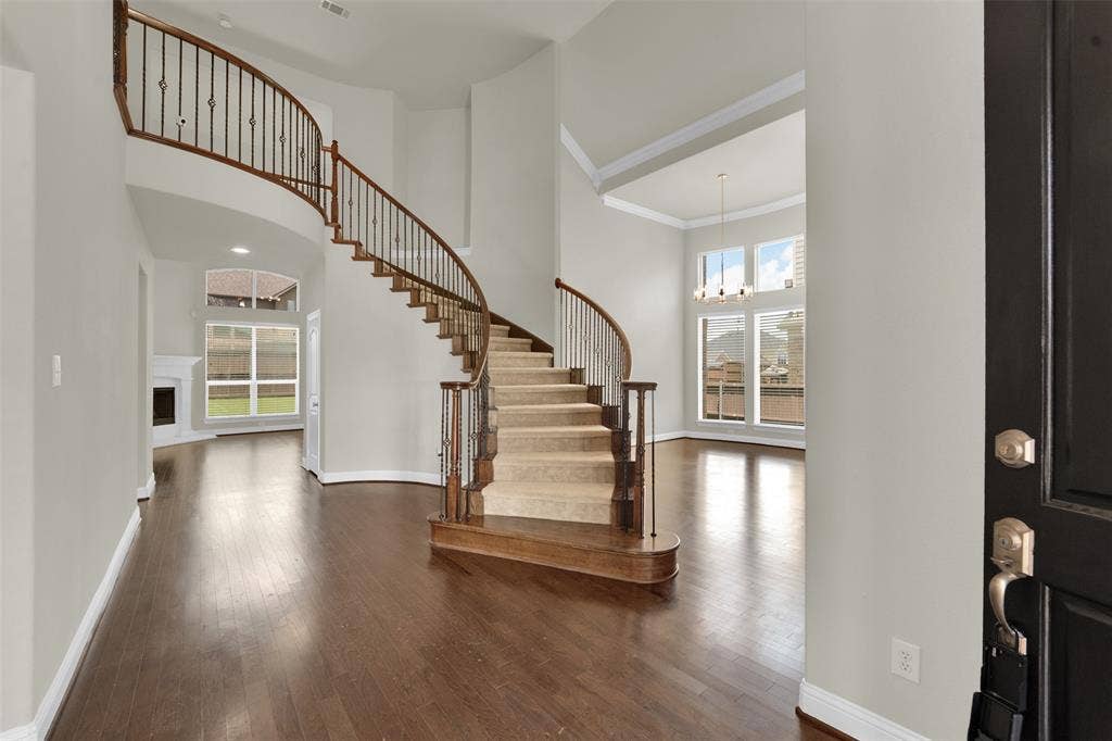 6811 Shady View Court, Sachse, TX 75048 Grand foyer featuring a curved staircase with wrought iron balusters and wood handrails